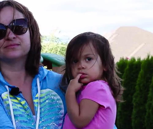 A woman in a blue shirt holds a little girl in a pink shirt