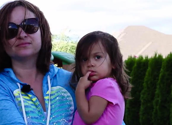 A woman in a blue shirt holds a little girl in a pink shirt