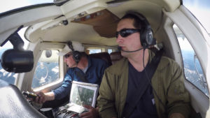 Jeff Lewis (left) listens for signals from below his airplane indicating the presence of fishers below in the Gifford Pinchot National Forest. CREDIT: KEN CHRISTIENSEN