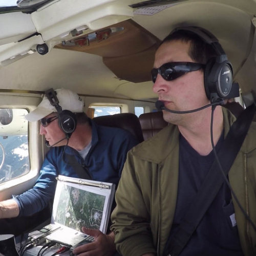 Jeff Lewis (left) listens for signals from below his airplane indicating the presence of fishers below in the Gifford Pinchot National Forest. CREDIT: KEN CHRISTIENSEN