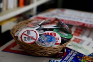 A bowl of buttons sit on top a pile of campaign signs against various fossil fuel projects in the Pacific Northwest. CREDIT: MOLLY SOLOMON