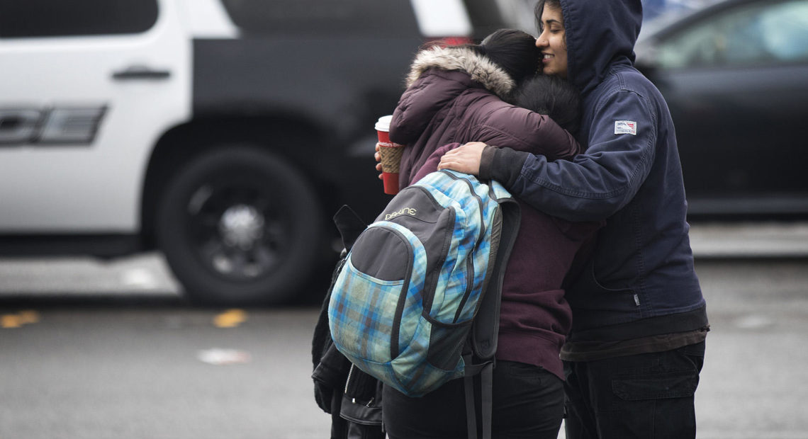 Harsimran Bagri, 24, right, and Gurkeert Bagri, 26, left, hug their 16-year-old sister, center, who was inside the college during the lockdown on Friday, Feb. 16, 2018, outside of Highline College in Des Moines. CREDIT: KUOW PHOTO/MEGAN FARMER