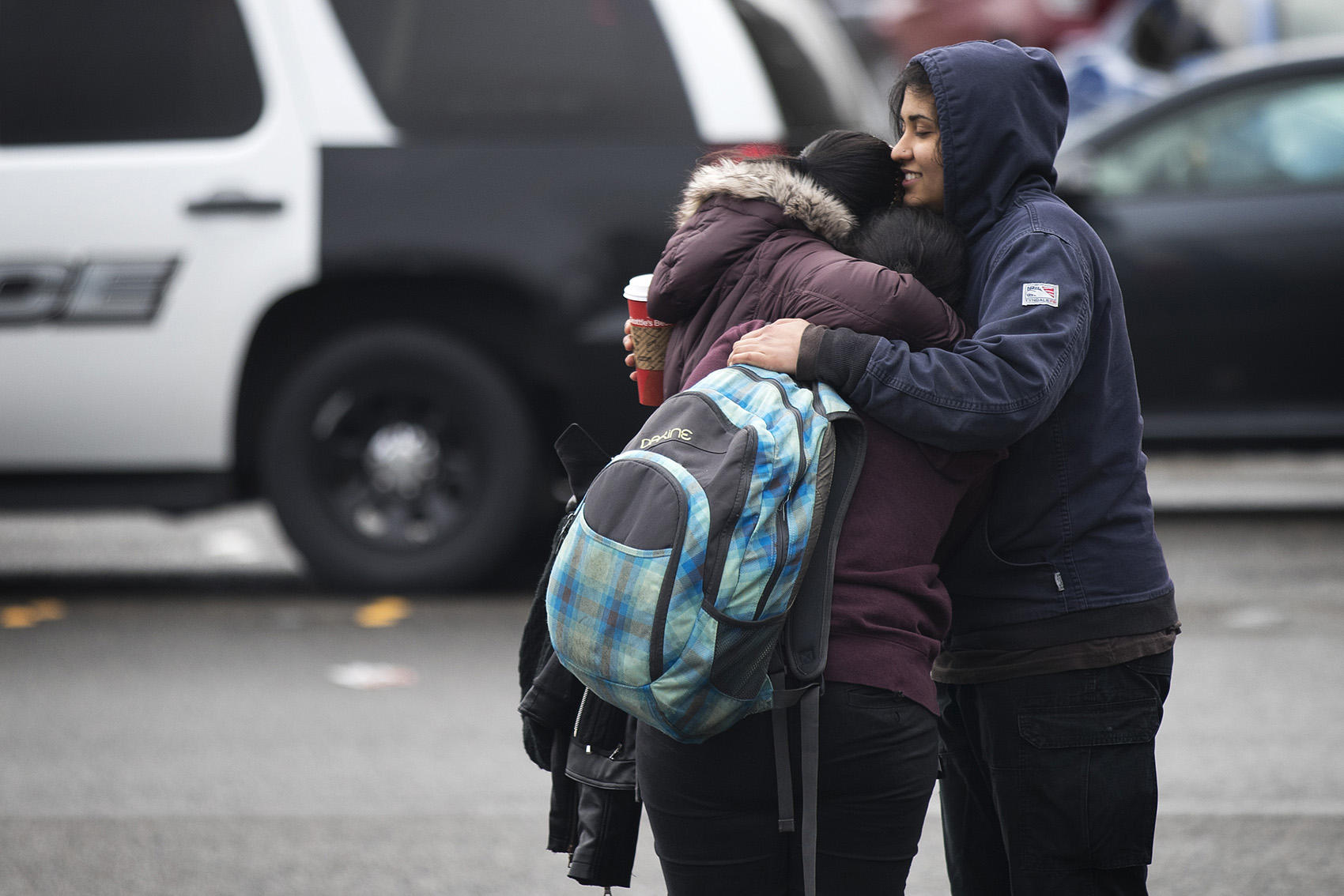 Harsimran Bagri, 24, right, and Gurkeert Bagri, 26, left, hug their 16-year-old sister, center, who was inside the college during the lockdown on Friday, Feb. 16, 2018, outside of Highline College in Des Moines. CREDIT: KUOW PHOTO/MEGAN FARMER