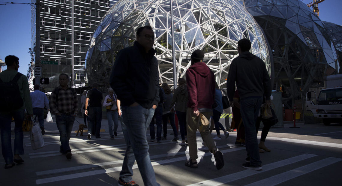 Pedestrians crossing the street in front of Amazon's headquarters in Seattle. CREDIT: MEGAN FARMER