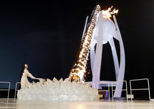 A torchbearer lights the Olympic flame. CREDIT: DAVID J PHILLIP/AP