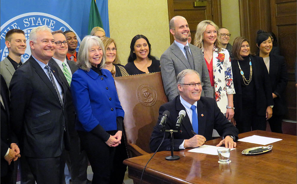 Washington state lawmakers and other supporters surround Gov. Jay Inslee at a net neutrality bill signing ceremony in Olympia Monday. CREDIT: TOM BANSE
