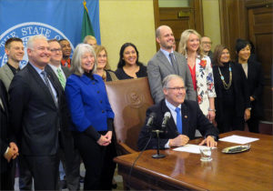 Washington state lawmakers and other supporters surround Gov. Jay Inslee at a net neutrality bill signing ceremony in Olympia Monday. CREDIT: TOM BANSE