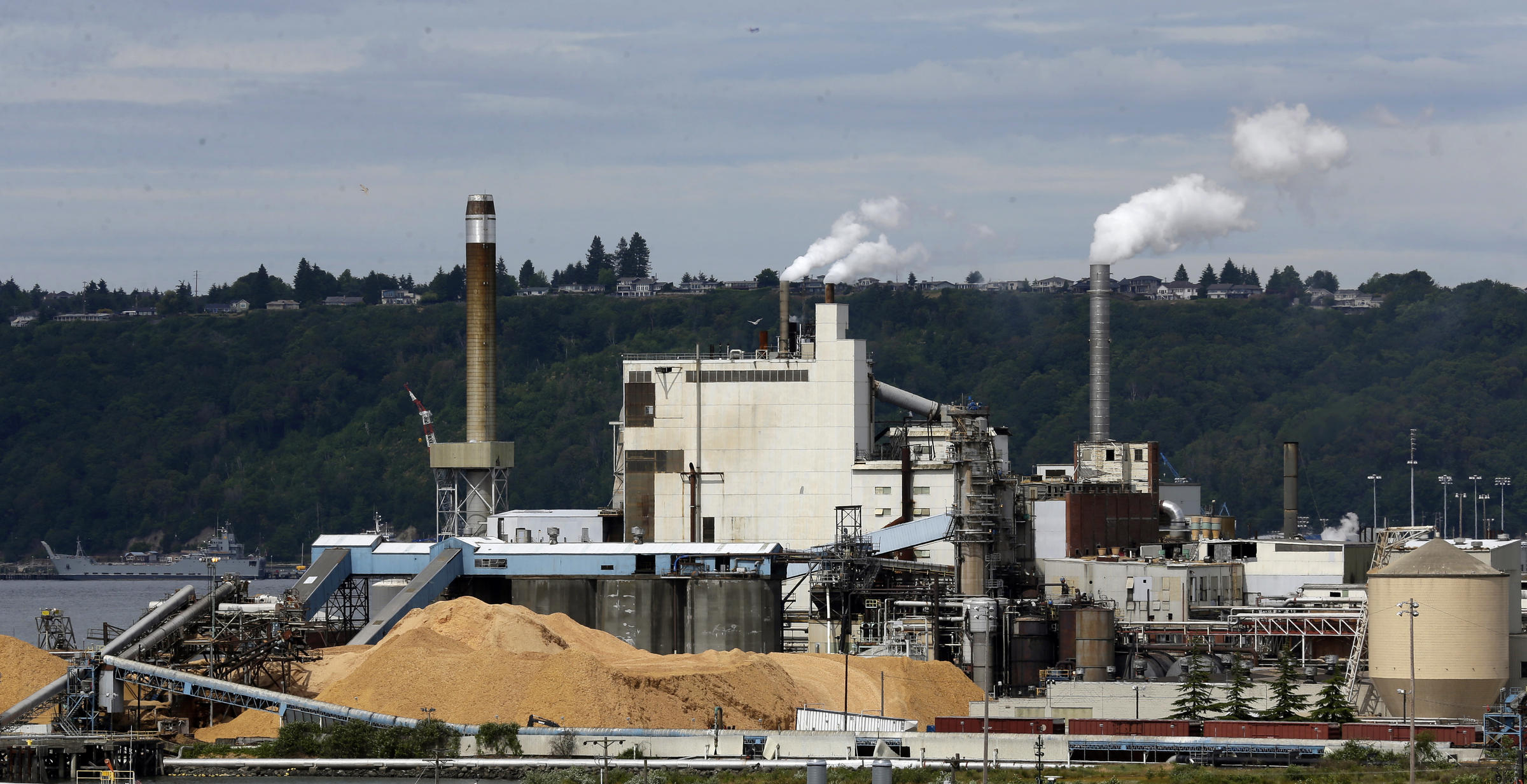 In this 2016, file photo, piles of wood chips sit near the RockTenn paper mill in Tacoma, Wash. Another ambitious effort to pass a carbon tax in Washington state has faltered as both Gov. Jay Inslee and the bill's prime sponsor conceded Thursday. CREDIT: TED S. WARREN, FILE / AP PHOTO