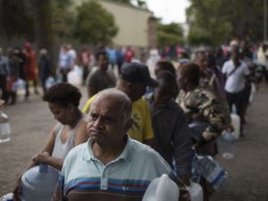 Residents wait to fill containers at a source for natural spring water in Cape Town, South Africa. CREDIT: Bram Janssen/AP