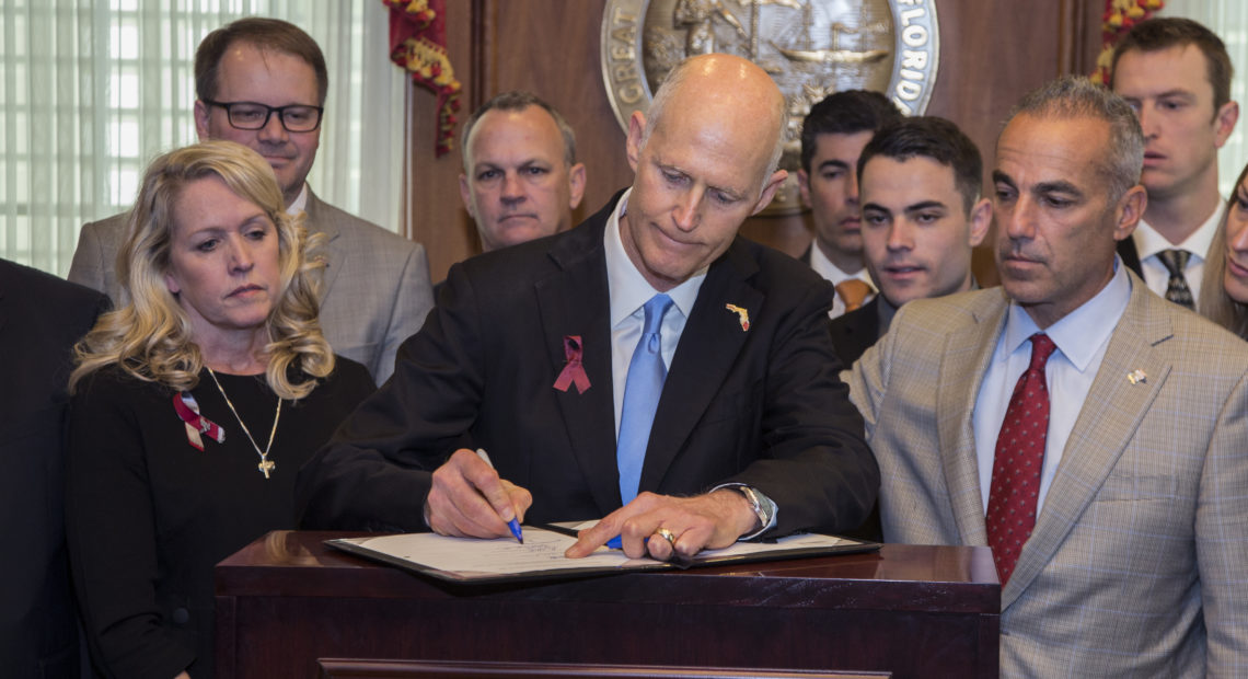 Florida Gov. Rick Scott signs the Marjory Stoneman Douglas Public Safety Act on Friday. The legislation includes a number of gun restrictions and also permits school personnel who are not full-time teachers to be armed