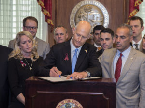 Florida Gov. Rick Scott signs the Marjory Stoneman Douglas Public Safety Act on Friday. The legislation includes a number of gun restrictions and also permits school personnel who are not full-time teachers to be armed