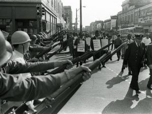 Striking Memphis sanitation workers march past Tennessee National Guard troops with fixed bayonets during a 20-block march to City Hall on March 29, 1968. Some 3,800 National Guard troops rolled into the city in armored tanks after the Tennessee legislature enacted a state of emergency. CREDIT: CHARLIE KELLY