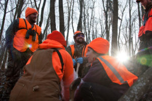 Tyler Hasheider (center) helps coach Beth Wojcik (bottom right) on how to clean a deer. They harvested two does during a day of hunting. CREDIT: NATE ROTT/NPR