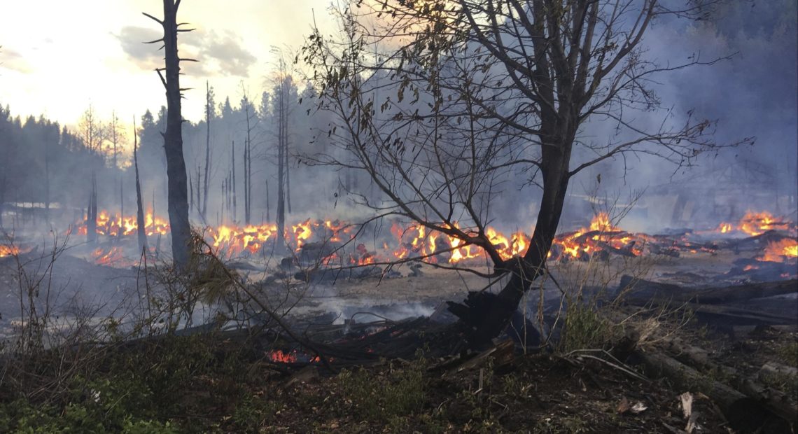 In this May 23, 2017 photo provided by Chelan County Fire District 3, logs burn near Leavenworth, Wash. The wildfire prompted evacuation orders for homes and cabins at a popular Washington state hiking and skiing destination. CREDIT: BEN TORKELSON