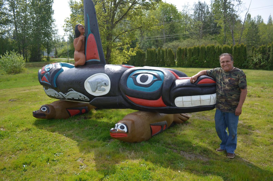 Lummi carver Jewell James stands with a totem pole he carved to urge the return of Tokitae the orca to Puget Sound. CREDIT: EILIS O'NEILL