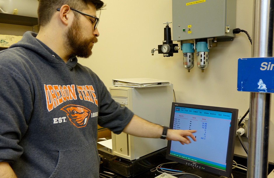 OSU researcher Byrne Miyamoto monitors how much weight a piece of Western Juniper can hold. CREDIT: JES BURNS