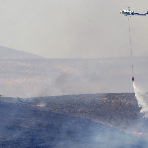 A helicopter uses a bucket to drop water on the Milepost 22 wildfire, Thursday, June 21, 2018, near Vantage, Wash. CREDIT: AP PHOTO/TED S. WARREN