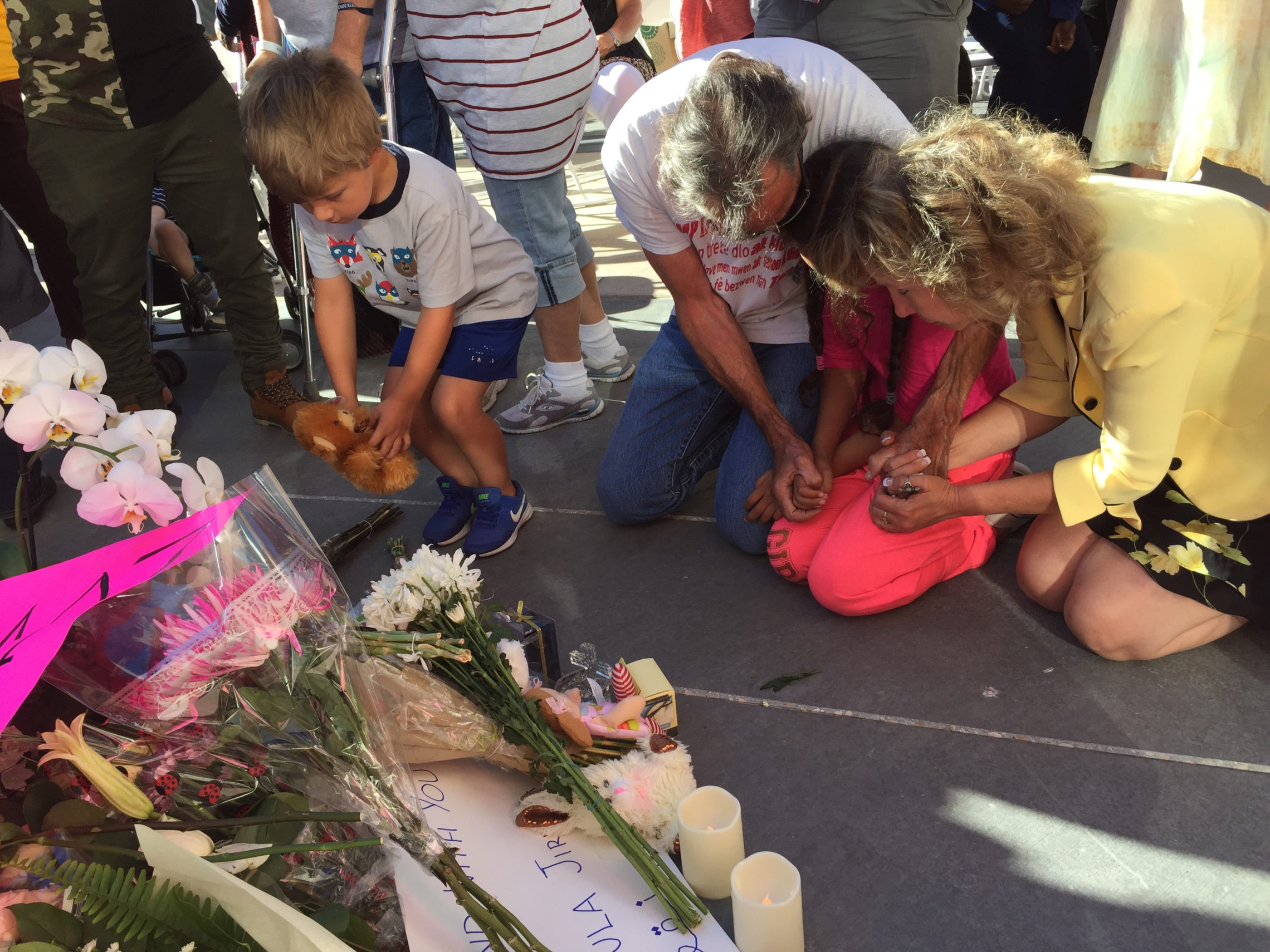 A boy places a stuffed animal as other people kneel at a memorial during a vigil at City Hall in Boise, Idaho, Monday, July 2, 2018. A 3-year-old Idaho girl who was stabbed at her birthday party died Monday, two days after a man invaded the celebration and attacked nine people with a knife, authorities said. AP Photo/Rebecca Boone