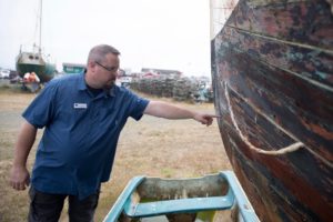 Troy Wood, derelict vessel removal program manager for the state Department of Natural Resources, points out damage on an aging wooden-hulled vessel that could be a “future customer” of a boat recycling center in Ilwaco, Washington. CREDIT: MATT M. MCKNIGHT