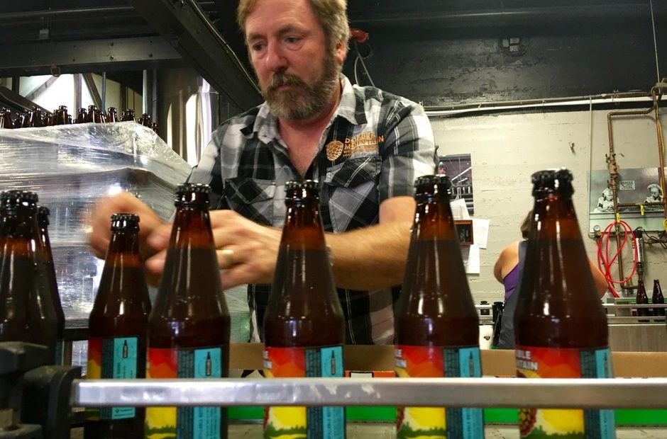 Double Mountain Brewery founder Matt Swihart grabs freshly bottled pale ale from the bottling line in Hood River. The brewery's new beer is among the first to be sold in Oregon's new refillable beer bottles. CREDIT: CASSANDRA PROFITA