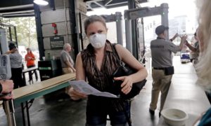 A fan enters the Seattle Mariners ballpark wearing a mask to help protect against smoky skies before a baseball game against in August 2018. CREDIT: ELAINE THOMPSON/AP