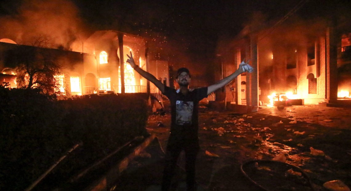 PHOTO: An Iraqi protester stands flashing the victory gesture outside the burning headquarters of the Iranian Consulate in Basra on Sept. 7. CREDIT: Haidar Mohammed Ali /AFP/Getty Images