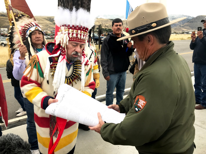 Chief Stanley Charles Grier of the Piikani Nation hands over a declaration to Yellowstone National Park deputy superintendent Pat Kenney. CREDIT: NATE HEGYI