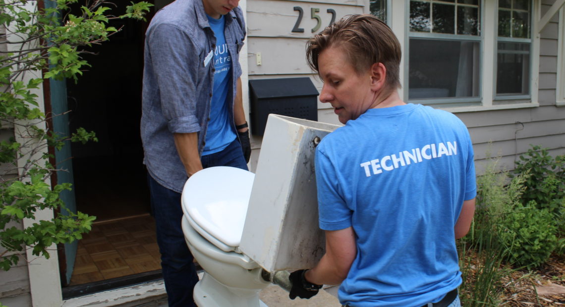 Resource Central employees Max Hartmann (left) and Neka Sunlin haul the MacFarland family's vintage toilet out of their Longmont, Colorado home. CREDIT: LUKE RUNYON/FOR NPR