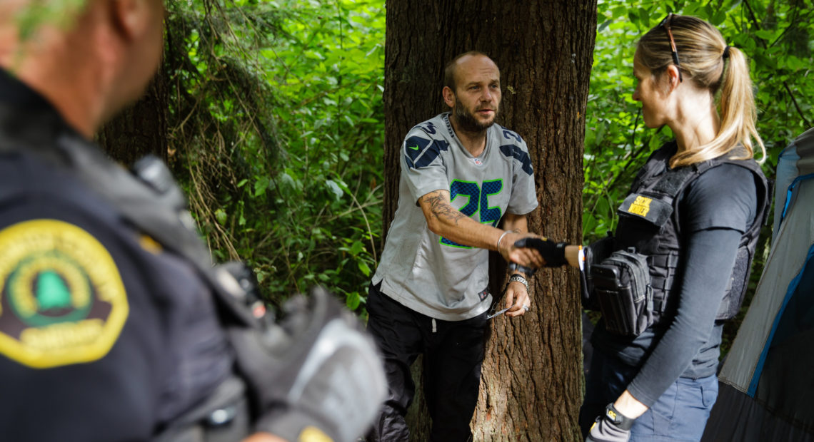 Social worker, Lauren Rainbow (right), meets a man illegally camped in the woods in Snohomish County. They are part of a new program in the county that helps people with addiction, instead of arresting them. CREDIT: Leah Nash for Finding Fixes Podcast