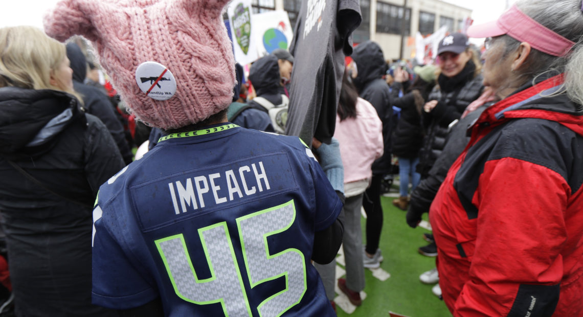 A woman wears a Seattle Seahawks jersey making reference to impeaching President Donald Trump as she takes part in a Women's March in Seattle, Saturday, Jan. 20, 2018. The march was one of dozens planned across the U.S. over the weekend. CREDIT: TED S. WARREN/AP