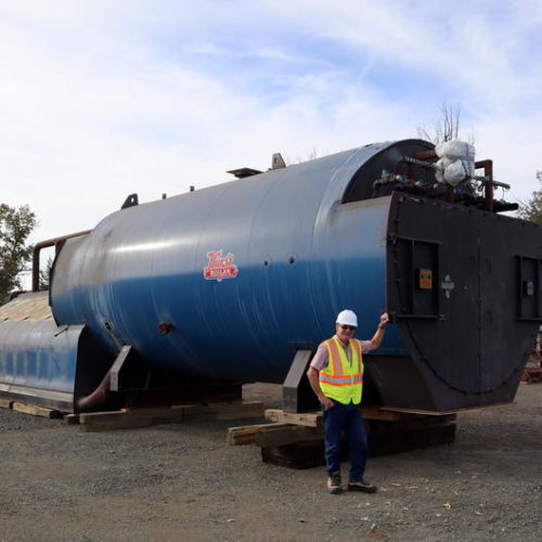 Biomass Operations Specialist John Rowell stands next to a boiler that awaits installation pending permits. TOM BANSE / NW NEWS NETWORK