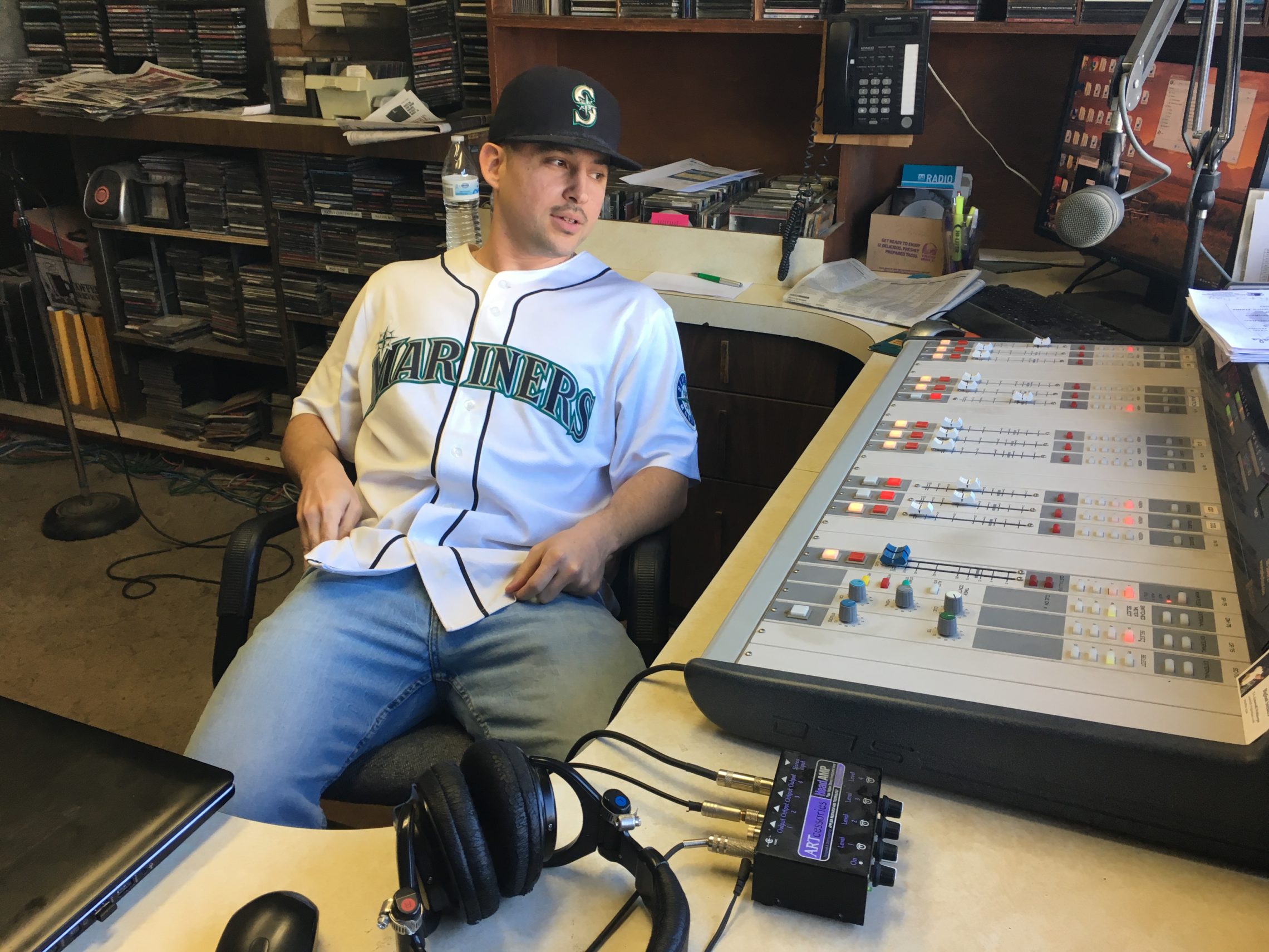KYNR host Ryan Craig at the station in February 2018, in front of the audio board that was stolen in October. CREDIT: Esmy Jimenez/NWPB