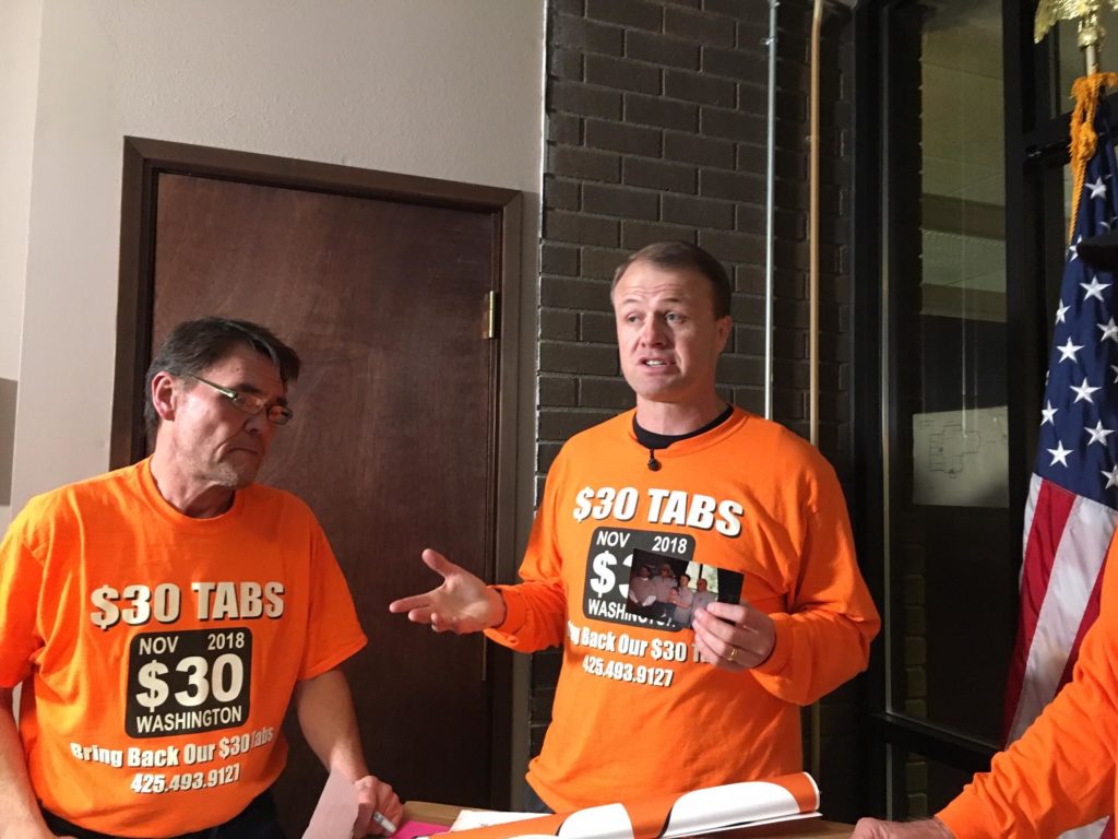 Professional initiative sponsor Tim Eyman, right, holds a photo from his first successful $30 car tabs initiative in 1999. Eyman says he has collected almost enough signatures to qualify a 2019 car tabs rollback initiative to the 2019 Legislature. CREDIT: AUSTIN JENKINS/N3