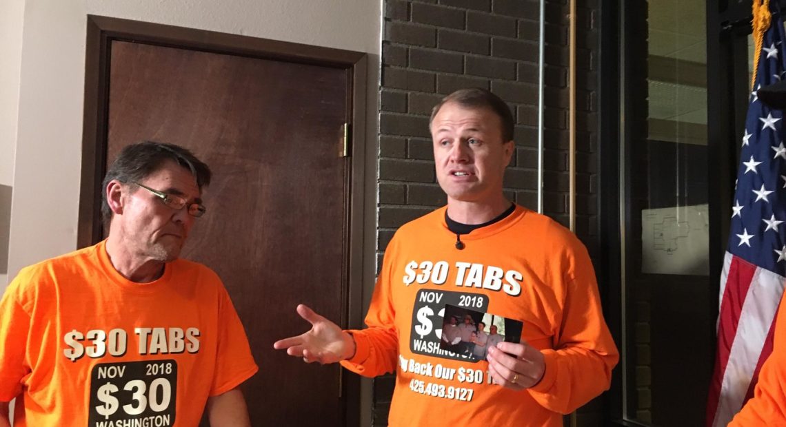 Professional initiative sponsor Tim Eyman, right, holds a photo from his first successful $30 car tabs initiative in 1999. Eyman says he has collected almost enough signatures to qualify a 2019 car tabs rollback initiative to the 2019 Legislature. CREDIT: AUSTIN JENKINS/N3