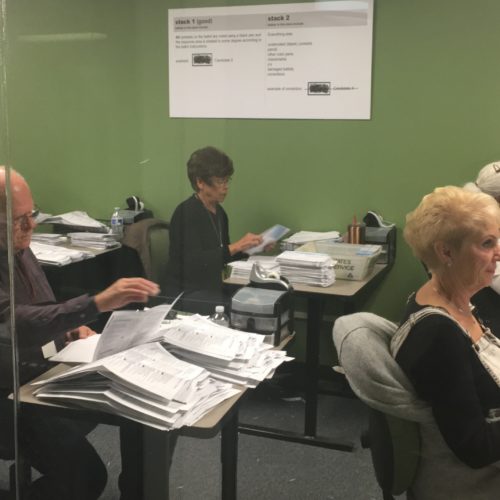 Workers in the Yakima County Elections Office work to open ballots and verify information. Their work is done within public view behind a glass wall, for anyone to monitor. CREDIT: ESMY JIMENEZ/NWPB