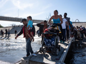 Migrants make their way across the almost-dry riverbed of the Tijuana River on their way to the El Chaparral port of entry to the U.S. in Tijuana, Mexico, on Nov. 25. CREDIT: Guillermo Arias /AFP/Getty Images