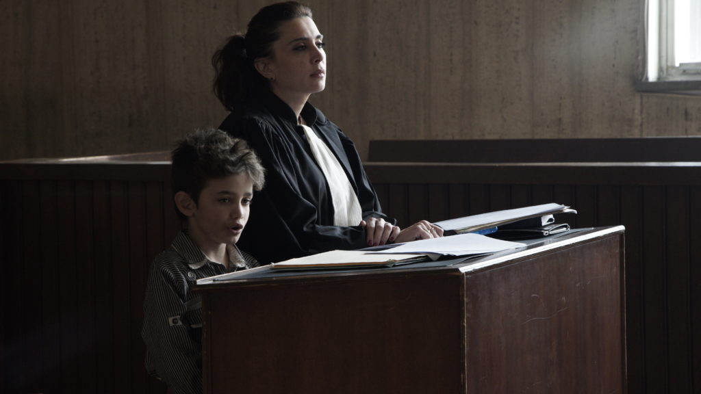 In Capernaum, Zain (Zain Al Rafeea) takes the stand to sue his parents. In a cameo appearance, his lawyer is played by the film's director, Nadine Labaki. CREDIT: Fares Sokhon/Sony Pictures Classics