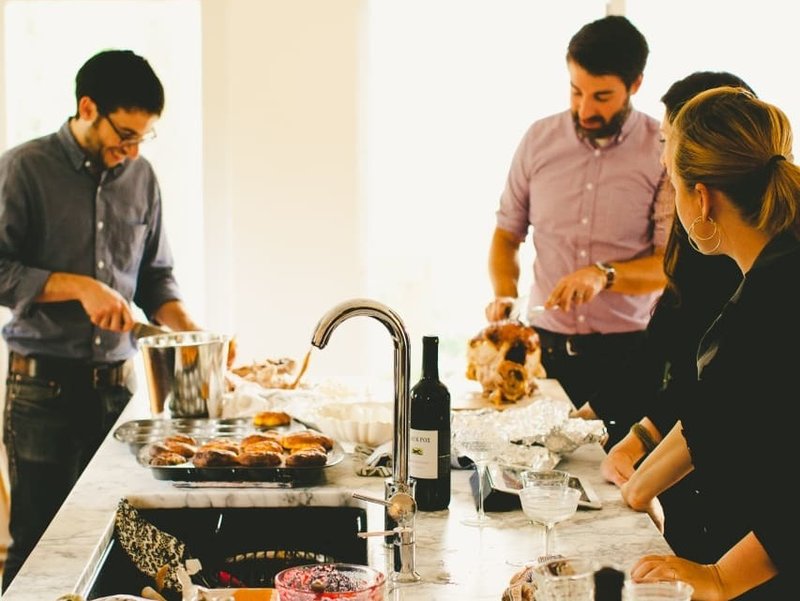 Michael Durand (left), husband of Kitchn Editor-In-Chief Faith Durand, and friend Chris Gardner (right) carve turkey while guests hang out in the Durands' kitchen, dirty dishes and all, at a recent party. CREDIT: Kitchn/Rachel Joy Barehl