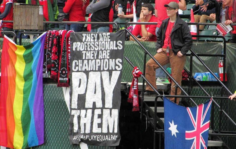 In this photo taken May 21, 2016, a sign calling for equitable pay in soccer is displayed at a Portland Thorns women’s soccer game at Providence Park in Portland. CREDIT: Anne M. Peterson/AP