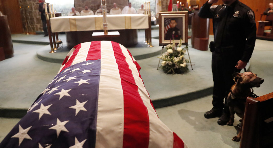 As of Dec. 27, this year 144 federal, state and local law enforcement officers have died in the line of duty — a rise from the 129 officers killed in 2017. Here, wounded Dekalb County Police K9 Indi stands by his handler's side during a funeral service for Edgar Flores on Dec. 18 in Georgia. CREDIT: John Bazemore/AP