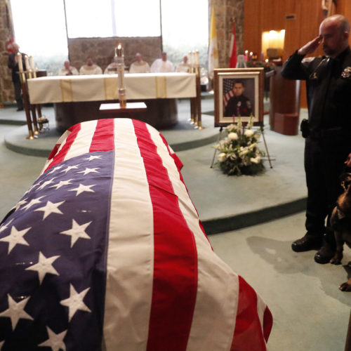 As of Dec. 27, this year 144 federal, state and local law enforcement officers have died in the line of duty — a rise from the 129 officers killed in 2017. Here, wounded Dekalb County Police K9 Indi stands by his handler's side during a funeral service for Edgar Flores on Dec. 18 in Georgia. CREDIT: John Bazemore/AP