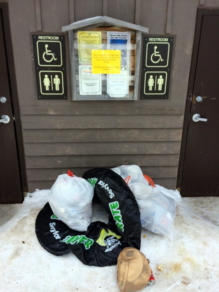 Trash stacked outside federal recreation site outhouse - Jan 2, 2019