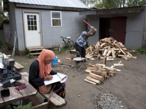 Seen in 2017, a girl studies for school while a man chops wood in the Muslim enclave of Islamberg in Tompkins, N.Y. Four people have been arrested in an alleged plot to attack the community. Mark Lennihan/AP