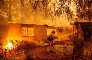 Firefighters battle flames at a burning apartment complex in Paradise, Calif., in November. State fire officials say power lines coming into contact with trees have sparked multiple Northern California wildfires in recent years. PG&E filed for bankruptcy on Tuesday. CREDIT: JOSH EDELSON/AFP/GETTY IMAGES