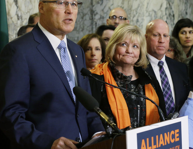 Washington Gov. Jay Inslee speaks in support of firearm restrictions in 2017, as his wife, Trudi, looks on. The initiative passed, but some Washington state sheriffs are refusing to enforce all the measures. CREDIT: Ted S. Warren/AP