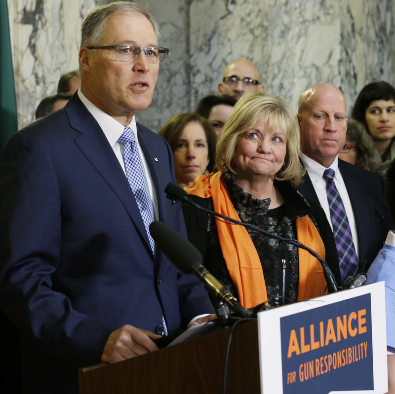 Washington Gov. Jay Inslee speaks in support of firearm restrictions in 2017, as his wife, Trudi, looks on. The initiative passed, but some Washington state sheriffs are refusing to enforce all the measures. CREDIT: Ted S. Warren/AP