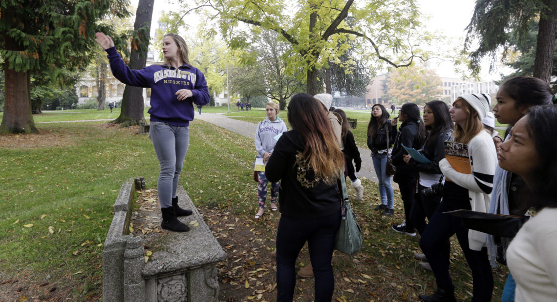 In this 2013 photo, University of Washington sophomore Megan Herndon, of Kailua, Hawaii, stands on a bench as she leads high school students on a tour of the campus in Seattle. CREDIT: ELAINE THOMPSON/AP