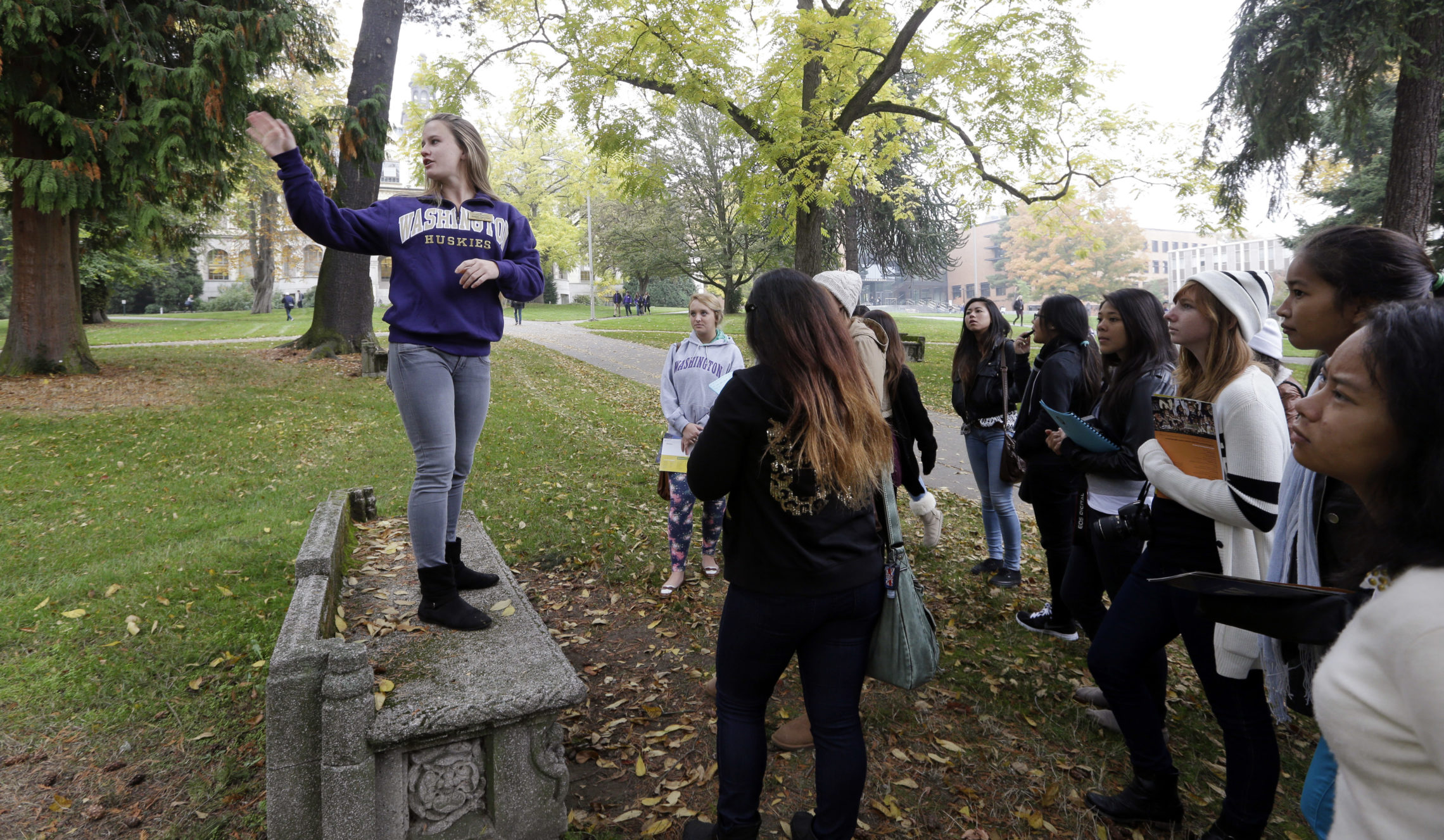 In this 2013 photo, University of Washington sophomore Megan Herndon, of Kailua, Hawaii, stands on a bench as she leads high school students on a tour of the campus in Seattle. CREDIT: ELAINE THOMPSON/AP