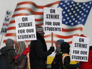 Teachers carry placards as they walk a picket line outside South High School early Monday in Denver. A new lawsuit alleges students with disabilities will be harmed by the strike.