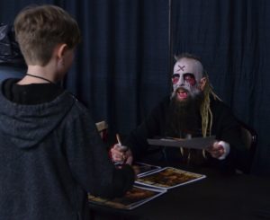 Wrestler with scary make up signs autographs for a young fan. 